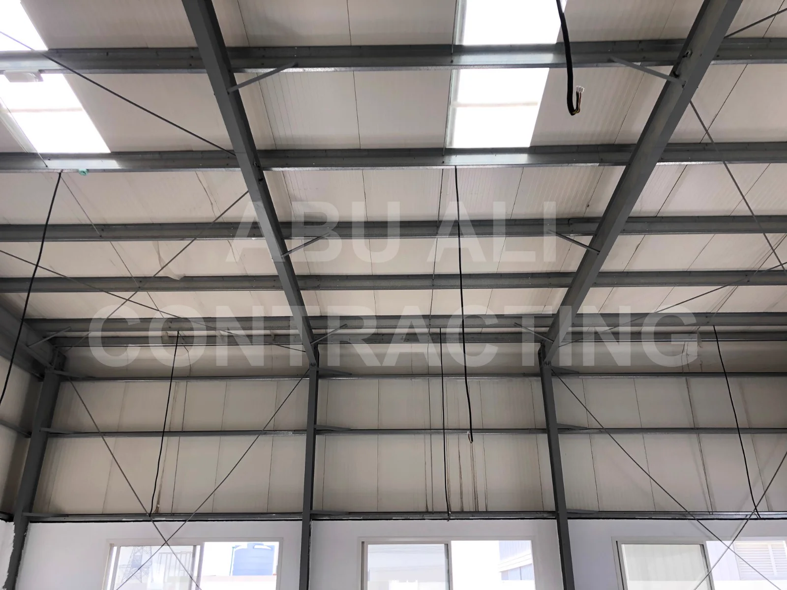 Detail of PEB warehouse steel rafters, purlin connections and tension bracing with insulated roof panels